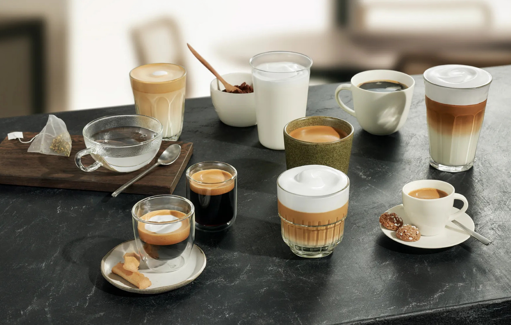Stół z różnymi napojami kawowymi, mlekiem, ciastkami i herbatą, przygotowany do degustacji kawy.