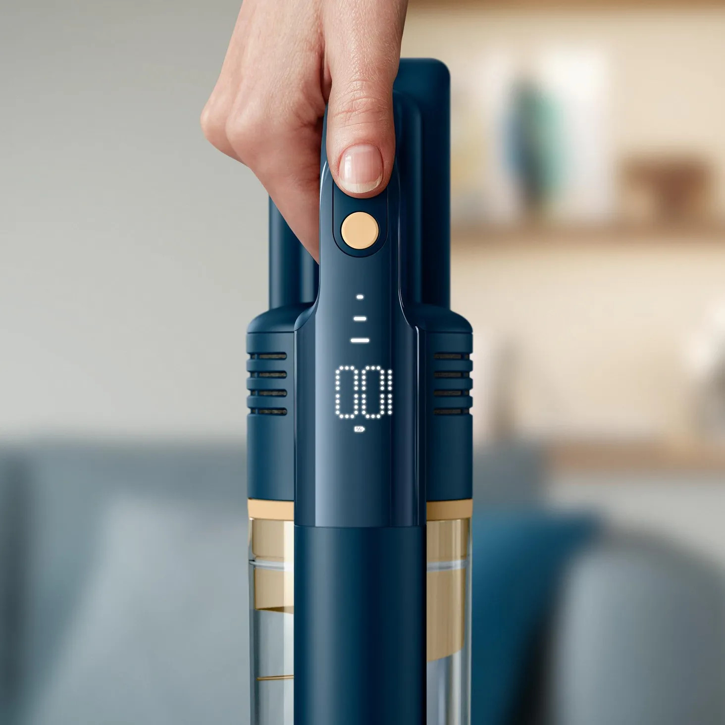 Dłoń trzymająca niebiesko-złoty odkurzacz.