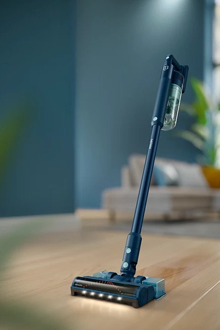 Niebieski odkurzacz bezprzewodowy na drewnianej podłodze.