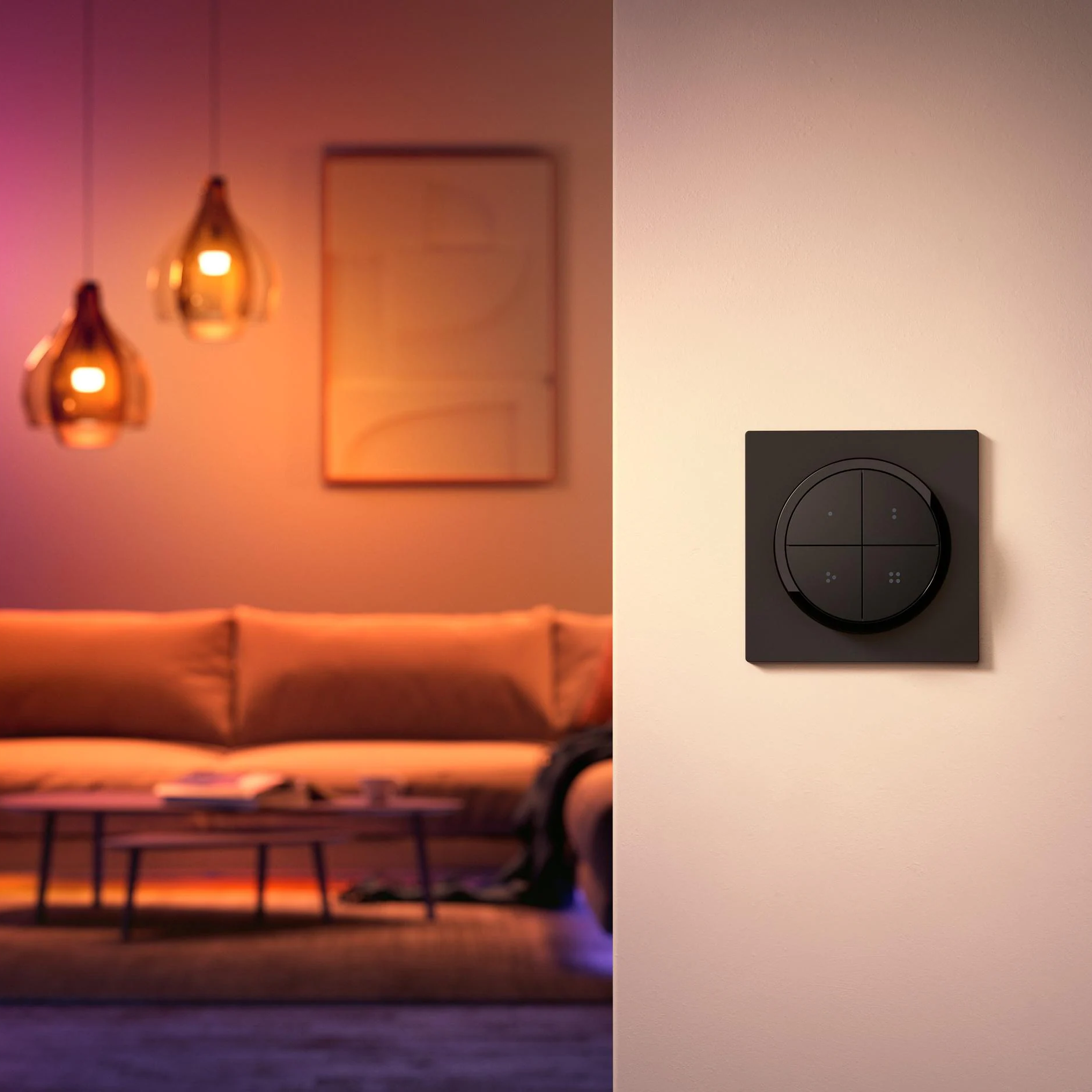 Scène de salon avec canapé, lampes suspendues et un interrupteur de lumière intelligent mural.
