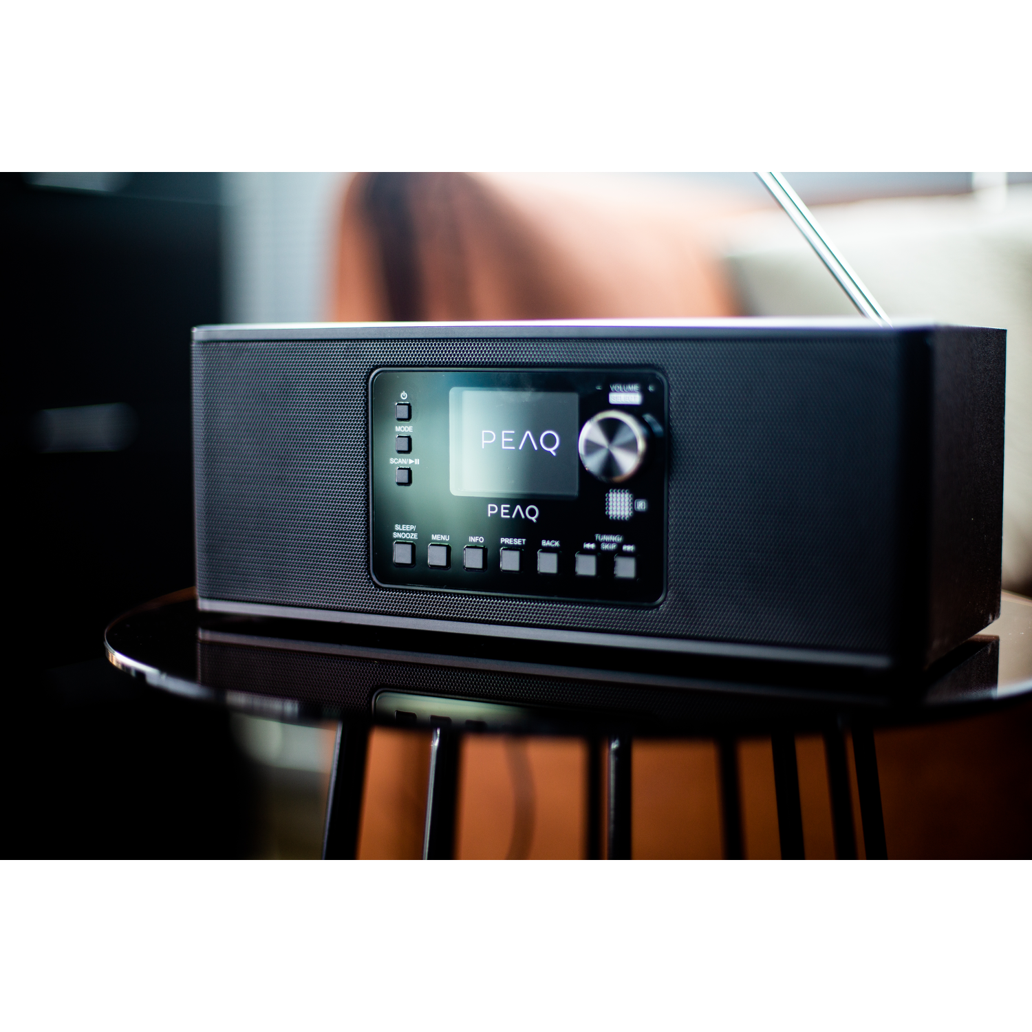 Black radio on a glass table, blurry background.