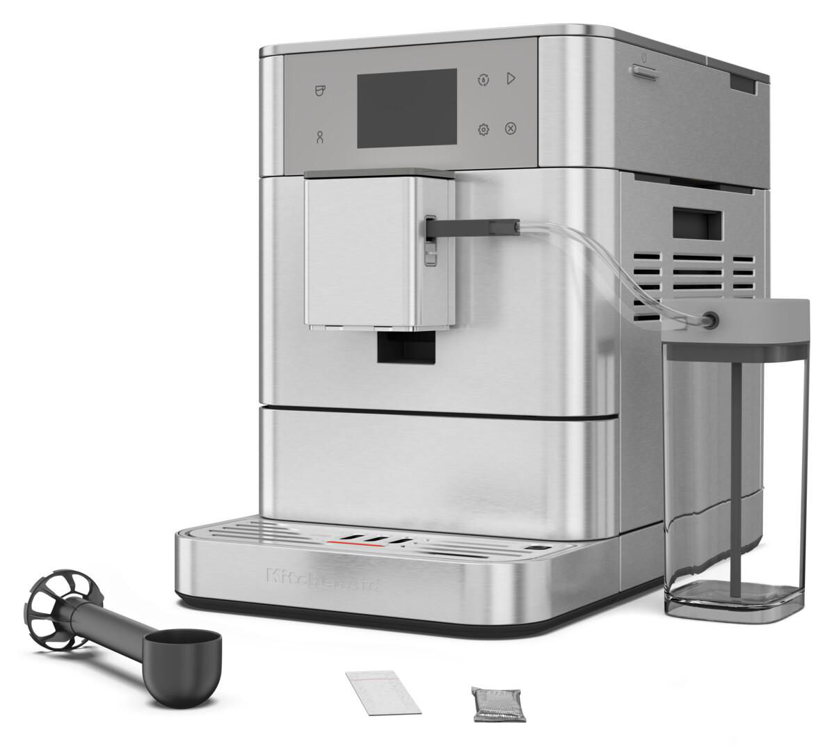 Silberfarbene KitchenAid Kaffeemaschine. Inklusive Zubehör: Messlöffel, Päckchen und Milchaufschäumer.