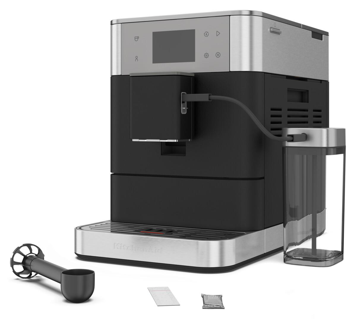 Eine schwarze und silberne KitchenAid-Kaffeemaschine mit Zubehör. Ein schwarzer Messlöffel ist vorne.