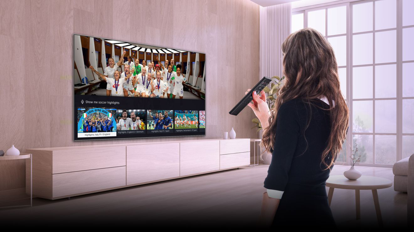 Nő távirányítóval, sportközvetítést néz a TV-n.