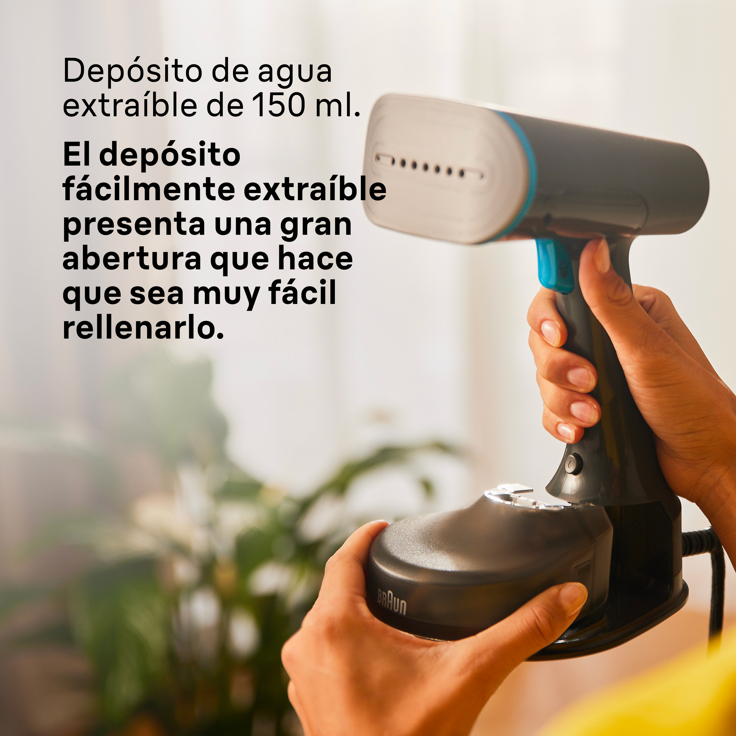 Una persona sosteniendo una plancha de vapor negra y turquesa, primer plano de la plancha y el agua.