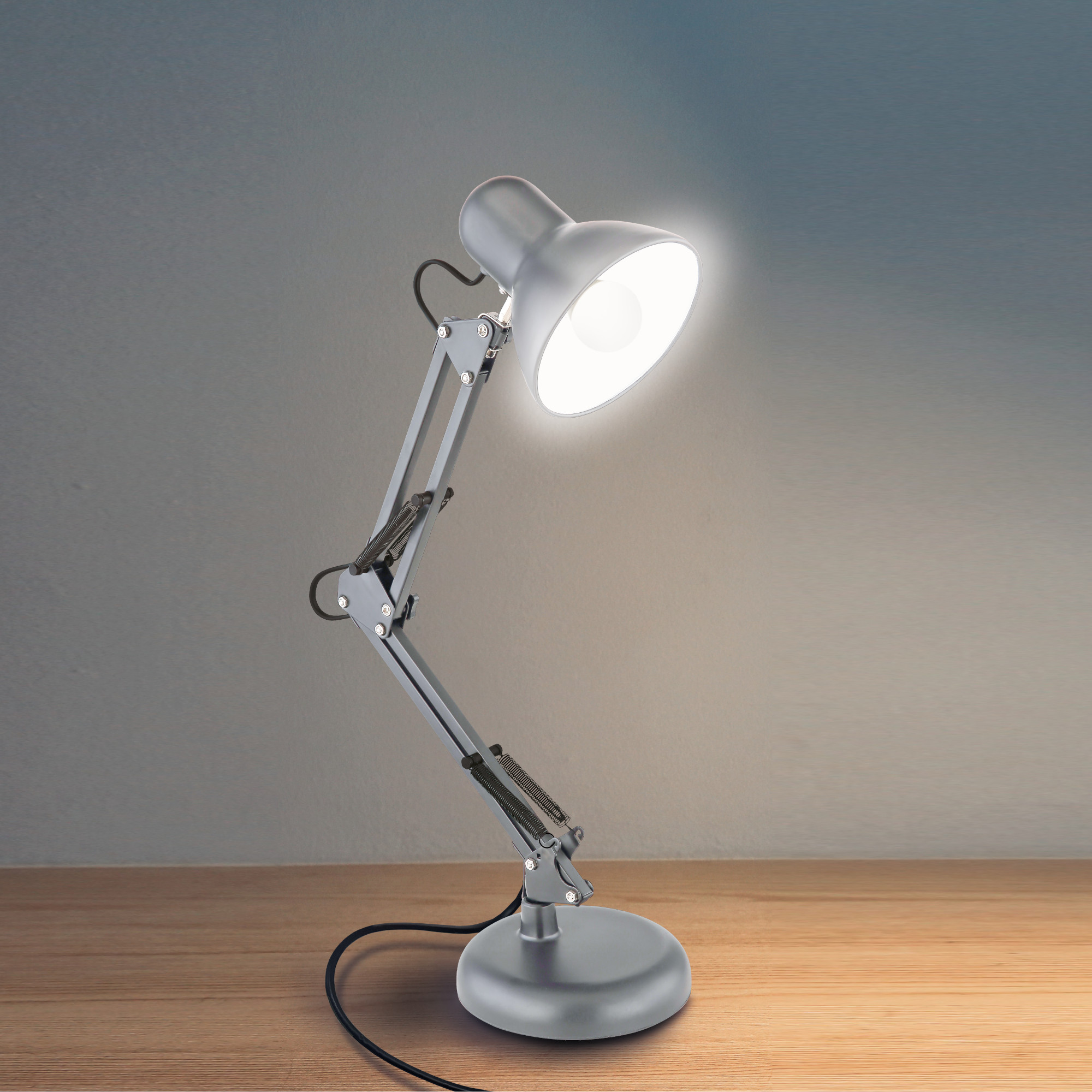 Eine silberne Schreibtischlampe mit hellem Licht auf einem Holztisch.
