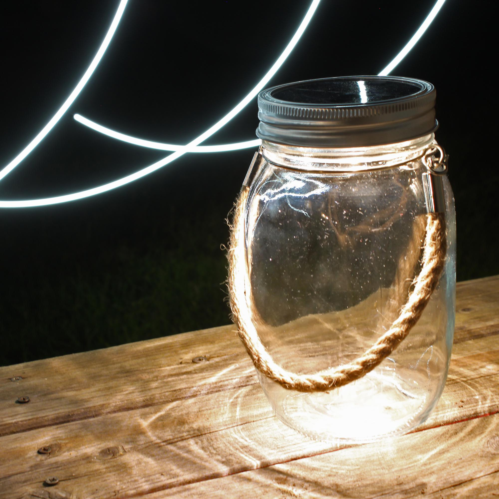 Leeres Glas mit Seilgriff auf Holz, mit weißen Lichtstreifen im Hintergrund.