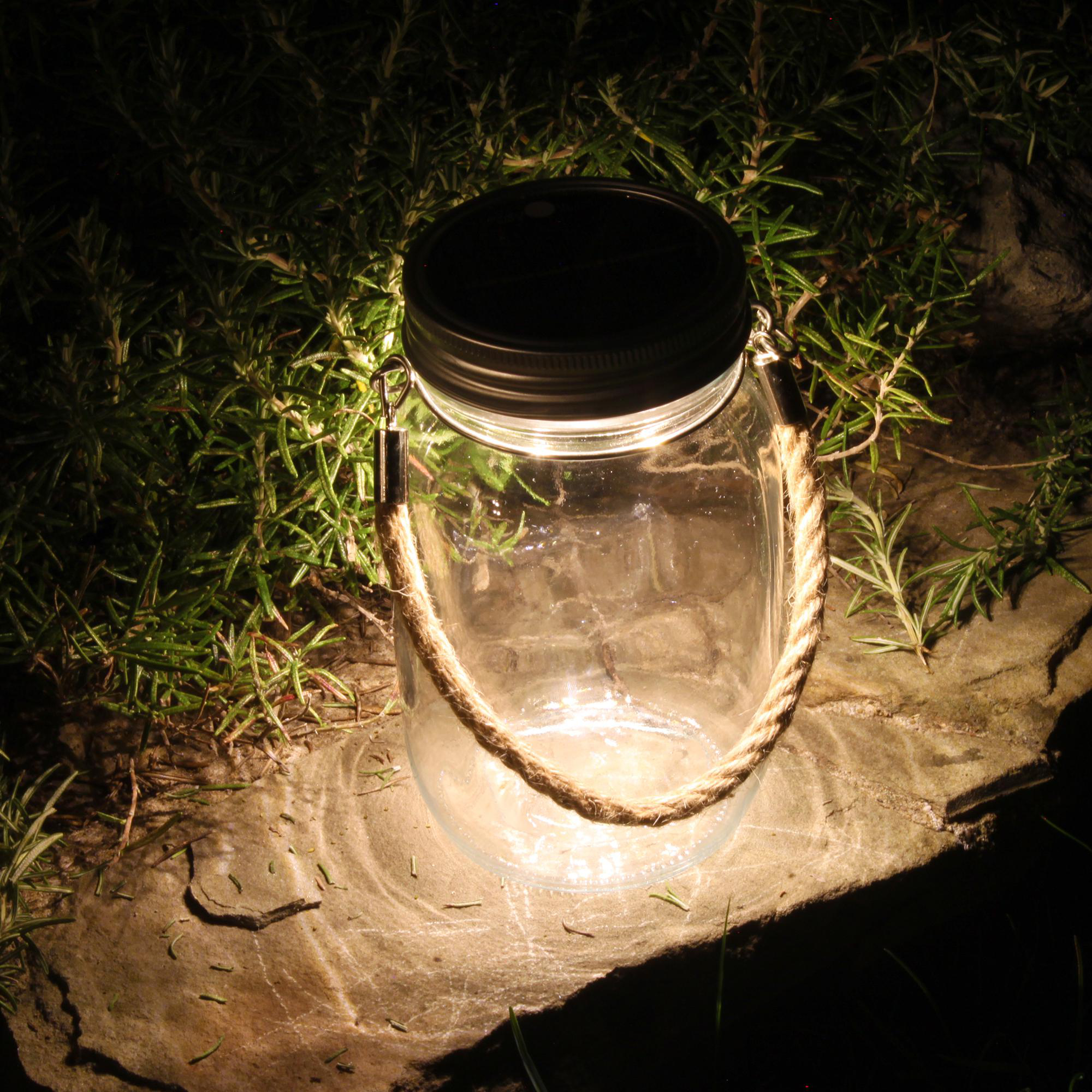 Ein Glas mit Deckel und Seilgriff, von innen beleuchtet. Auf einem Stein.
