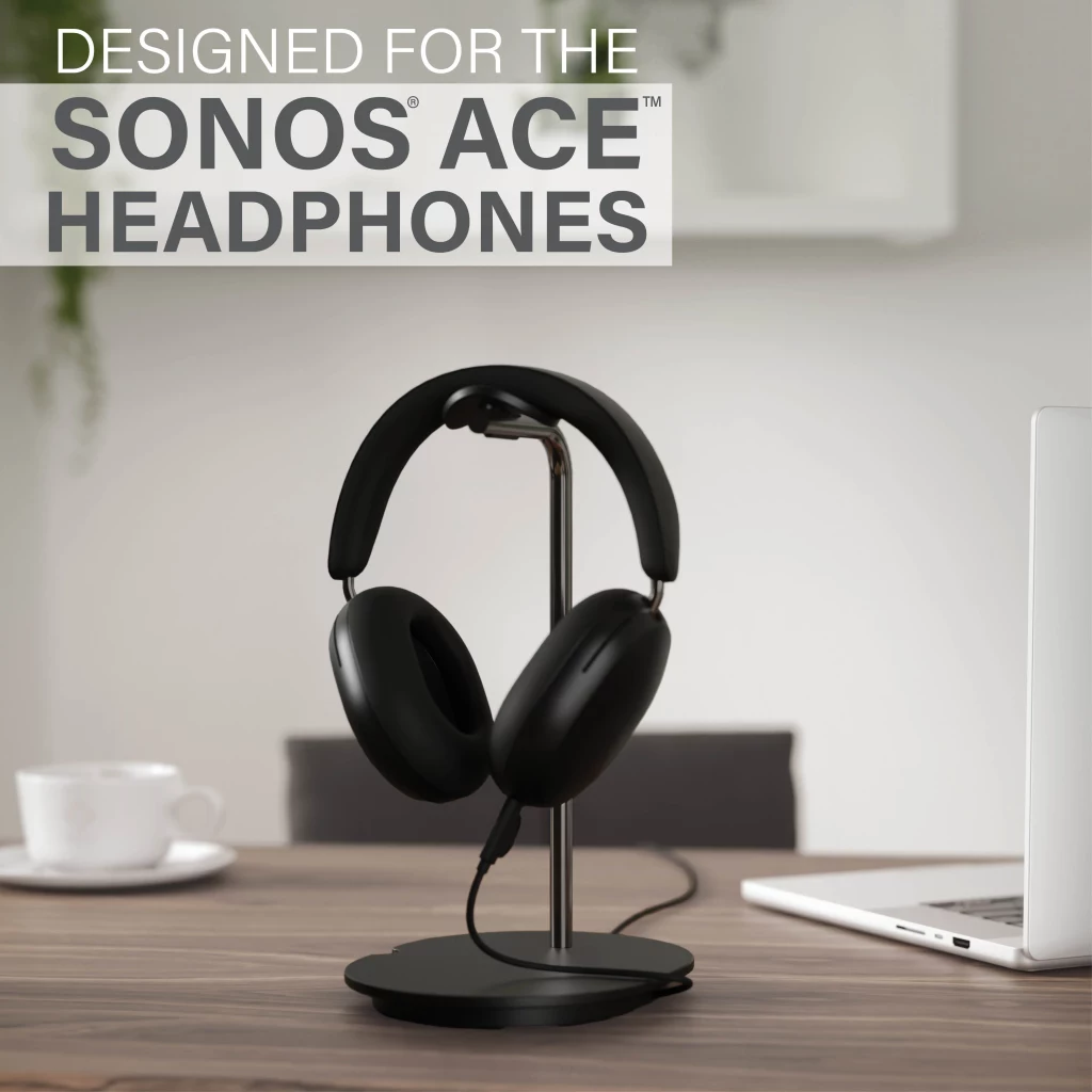 Casque noir sur un support à côté d'une tasse et d'un ordinateur portable.