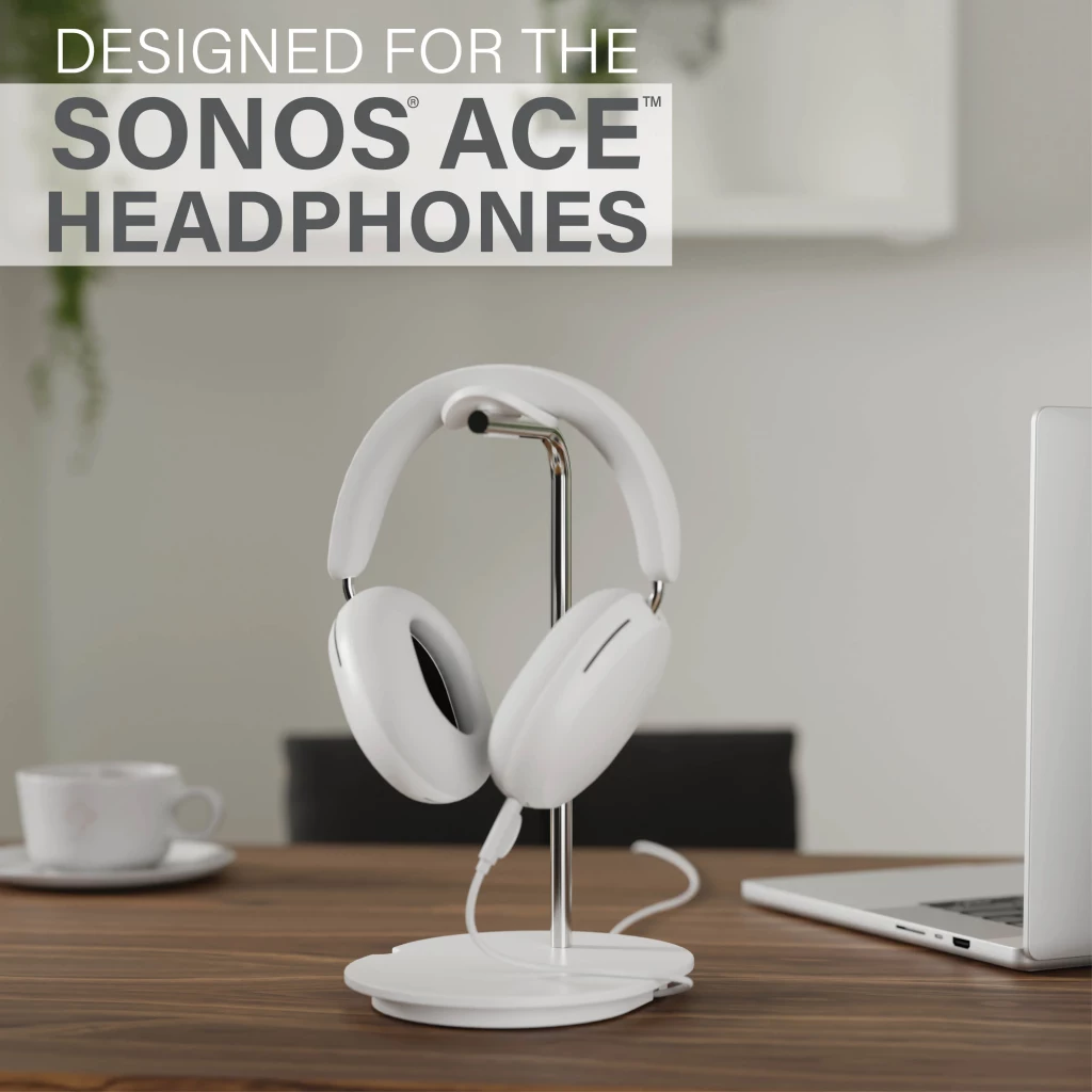 Casque blanc posé sur un support à côté d'une tasse à café et d'un ordinateur portable.