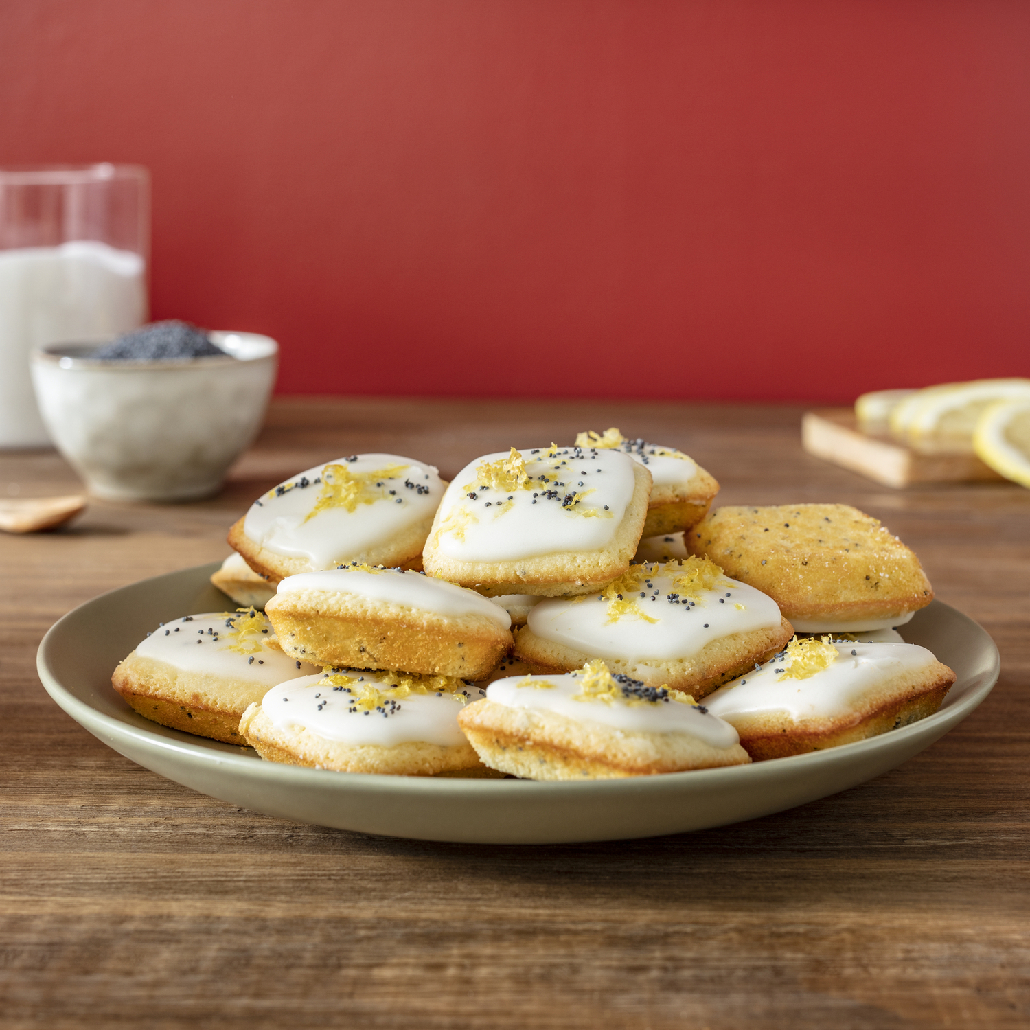 Koekjes, geglazuurd met witte glazuur en versierd met maanzaad, geserveerd op een groene schaal.