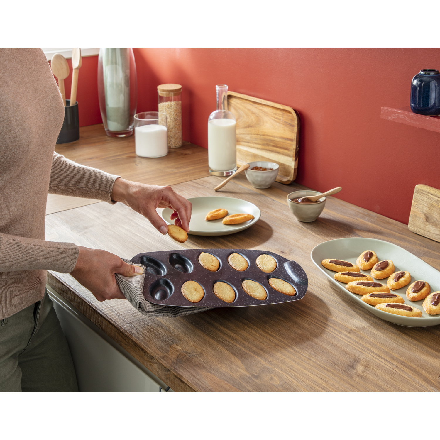 Une personne place un petit gâteau sur une assiette. Moule et autres aliments.