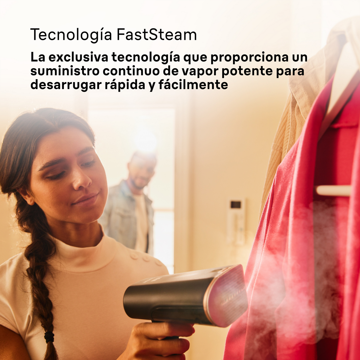 Una mujer usa un vaporizador en una prenda roja. Un hombre está en el fondo. El texto describe la tecnología FastSteam.
