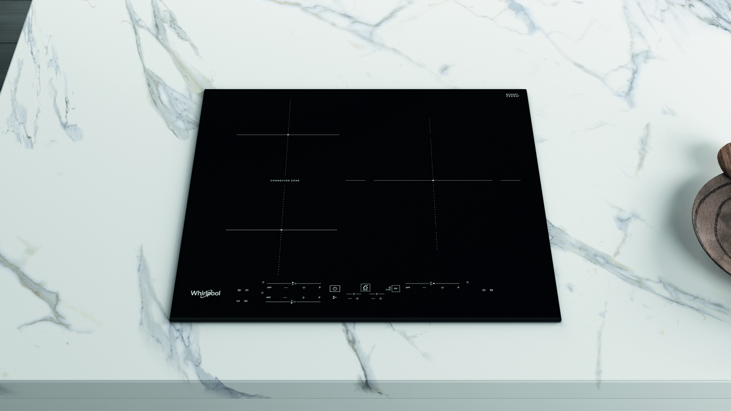Placa de inducción negra sobre encimera de mármol. Tiene cuatro fuegos y controles táctiles.