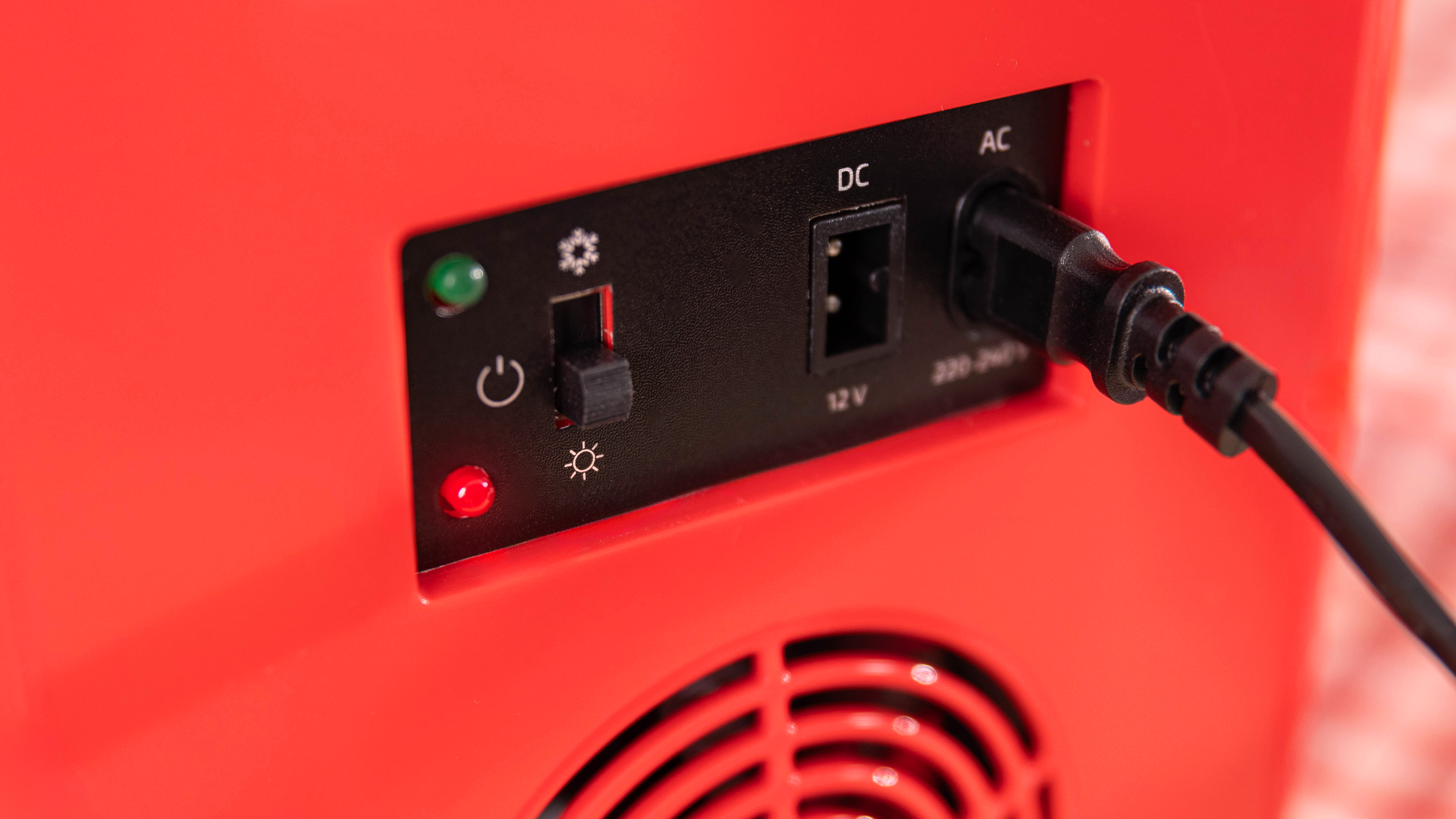Primer plano de un electrodoméstico rojo. Interruptor de encendido, indicadores y entrada de energía.