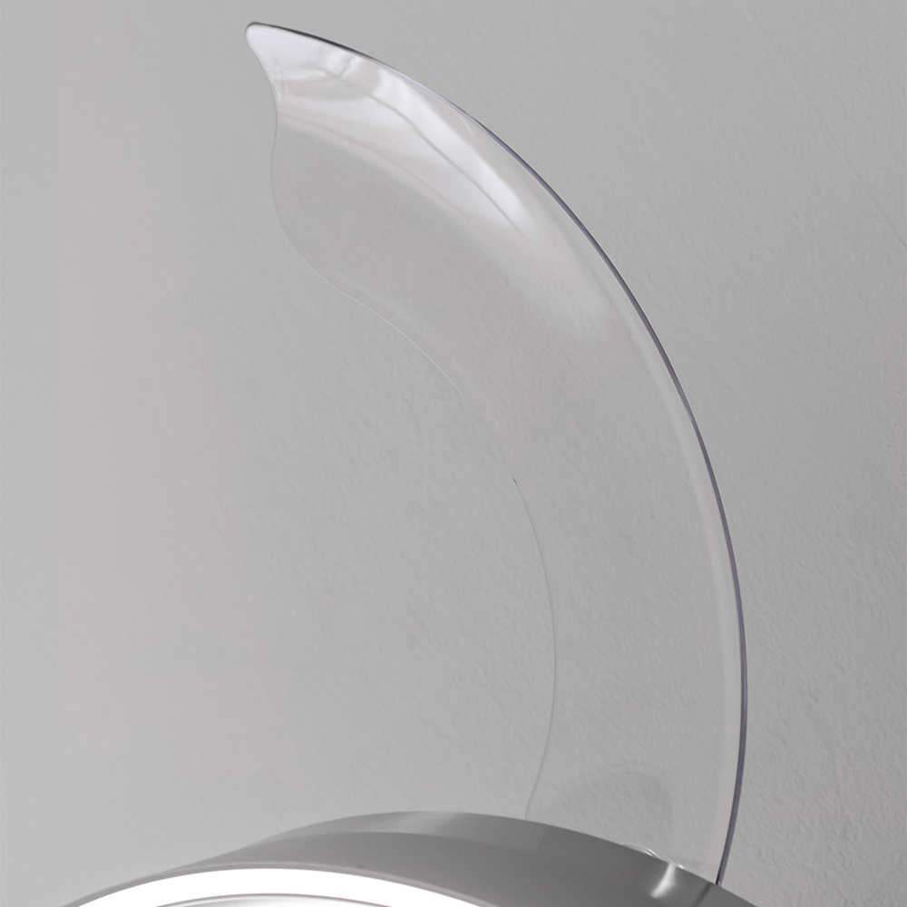 Una aspa de ventilador transparente frente a una pared blanca, mostrando una curva.