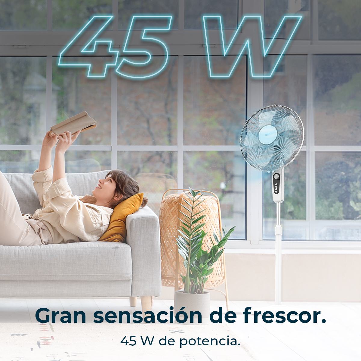 Mujer en el sofá leyendo un libro. Un ventilador está en el fondo, con un texto de potencia. Ventana en el fondo.