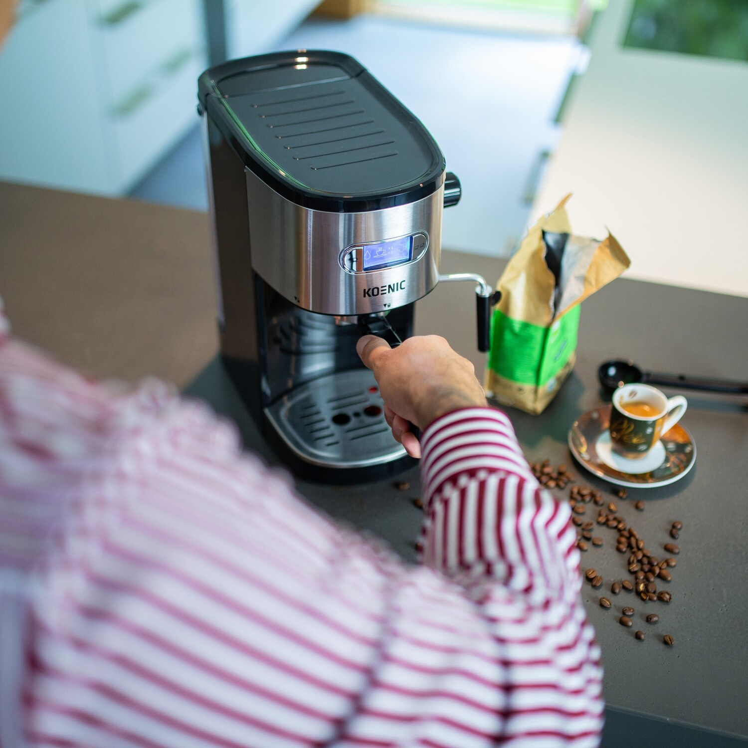 Une personne utilise une cafetière, avec des grains de café et une tasse à proximité.