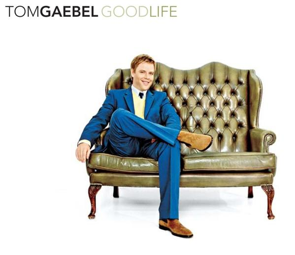 Ein Mann im Anzug sitzt auf einer grünen Couch. Der Text lautet 'Tom Gaebel Goodlife'.