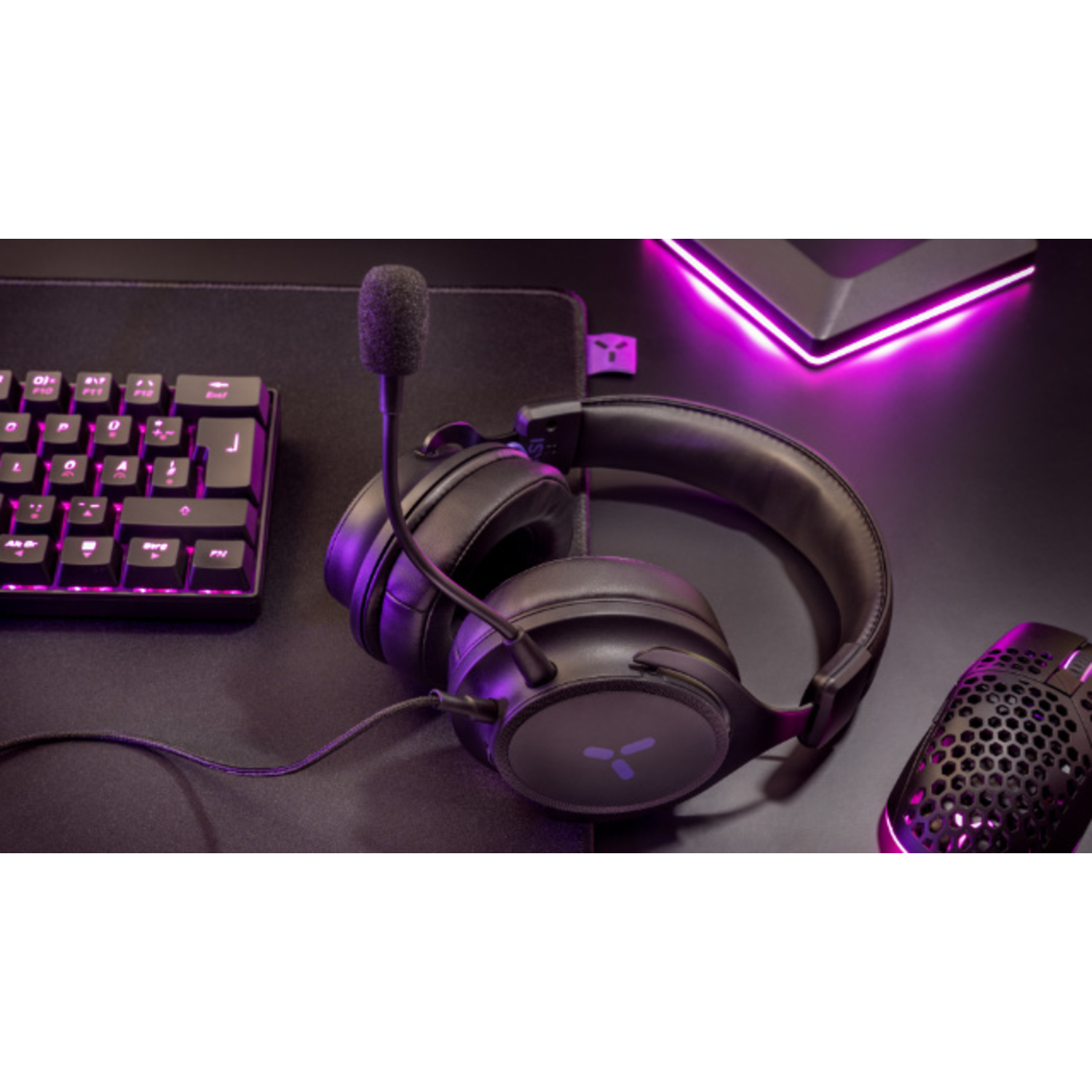 A black gaming headset with a microphone, keyboard, and mouse on a black surface.
