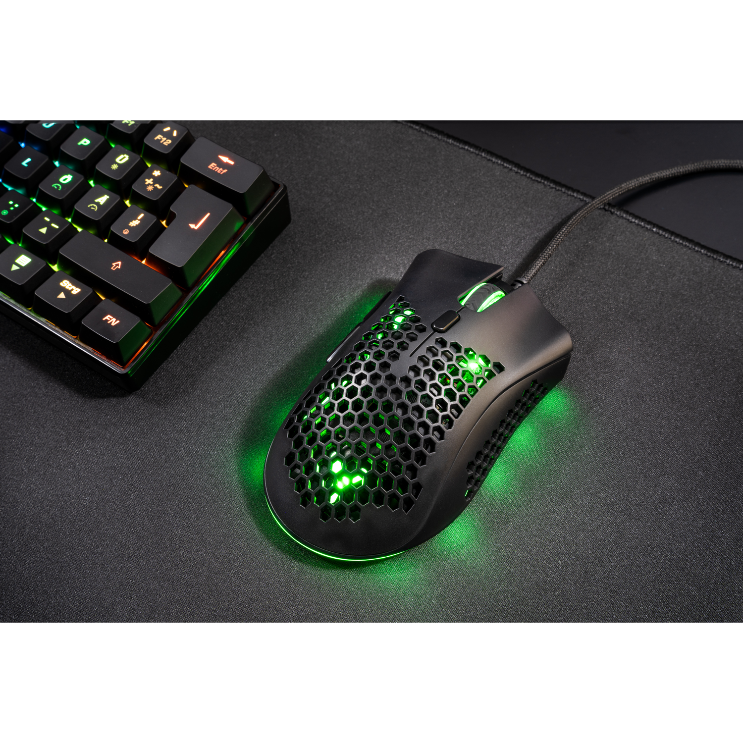 Black gaming mouse with green lights. A keyboard is visible in the background.