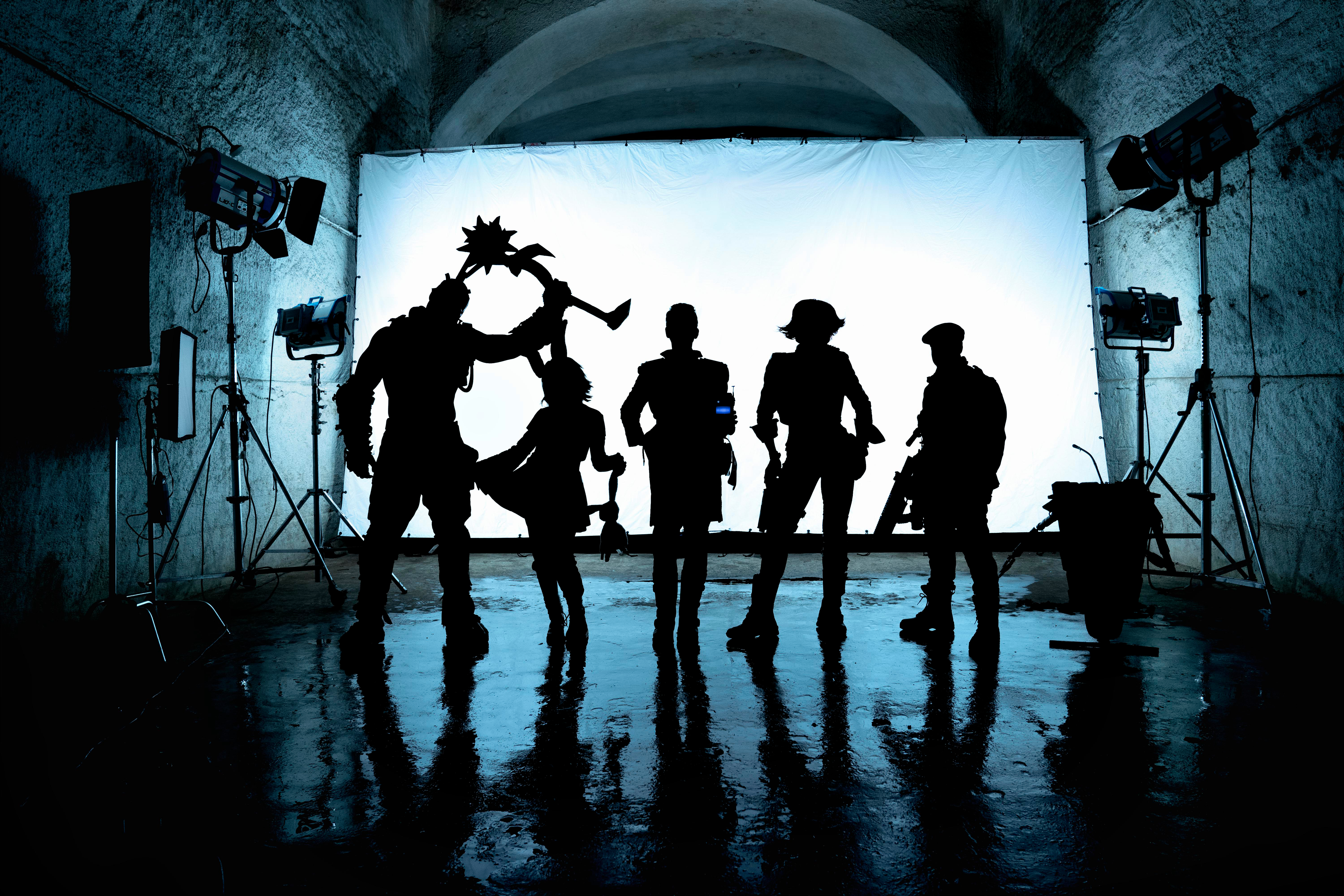 Silhouetten von Figuren auf der Bühne mit Lichttechnik. Sie halten Requisiten, eine Leinwand im Hintergrund.
