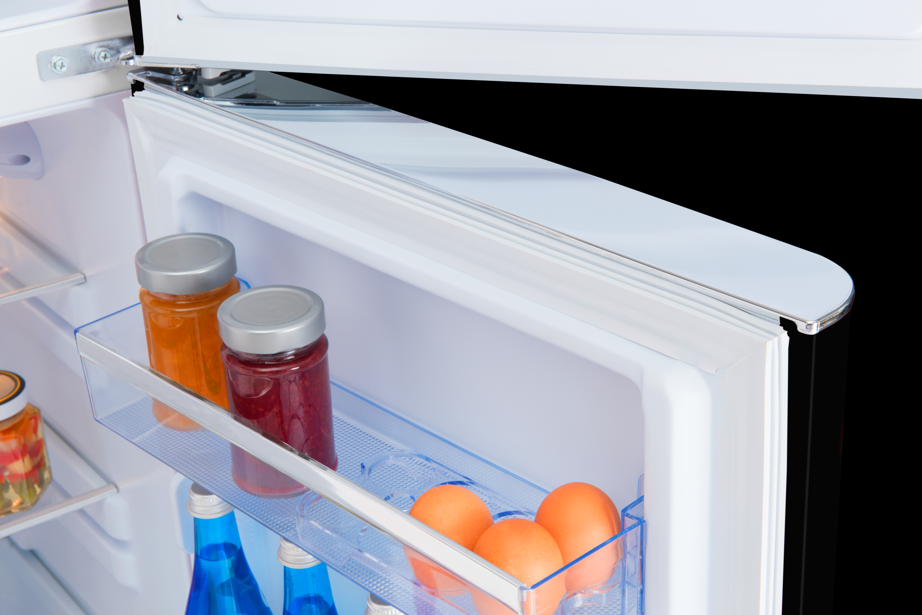 Innenseite eines Kühlschranks mit Marmeladengläsern, Eiern und Flaschen.