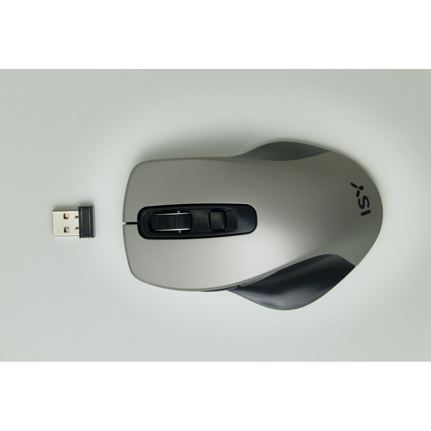 Gray wireless mouse with a USB receiver on a white surface, top-down view.