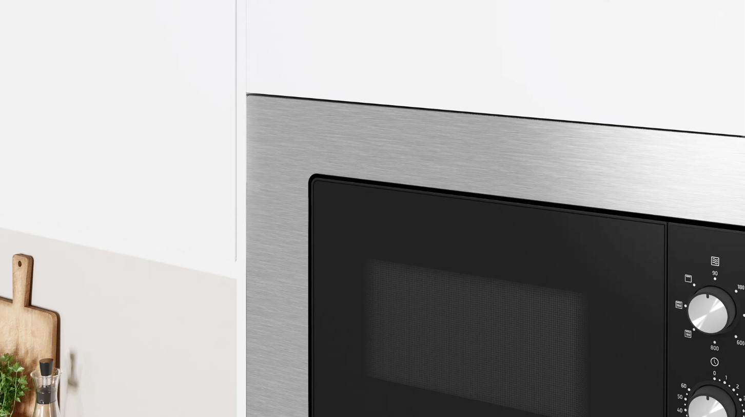 Un horno microondas, frente negro con marco plateado y armario blanco.