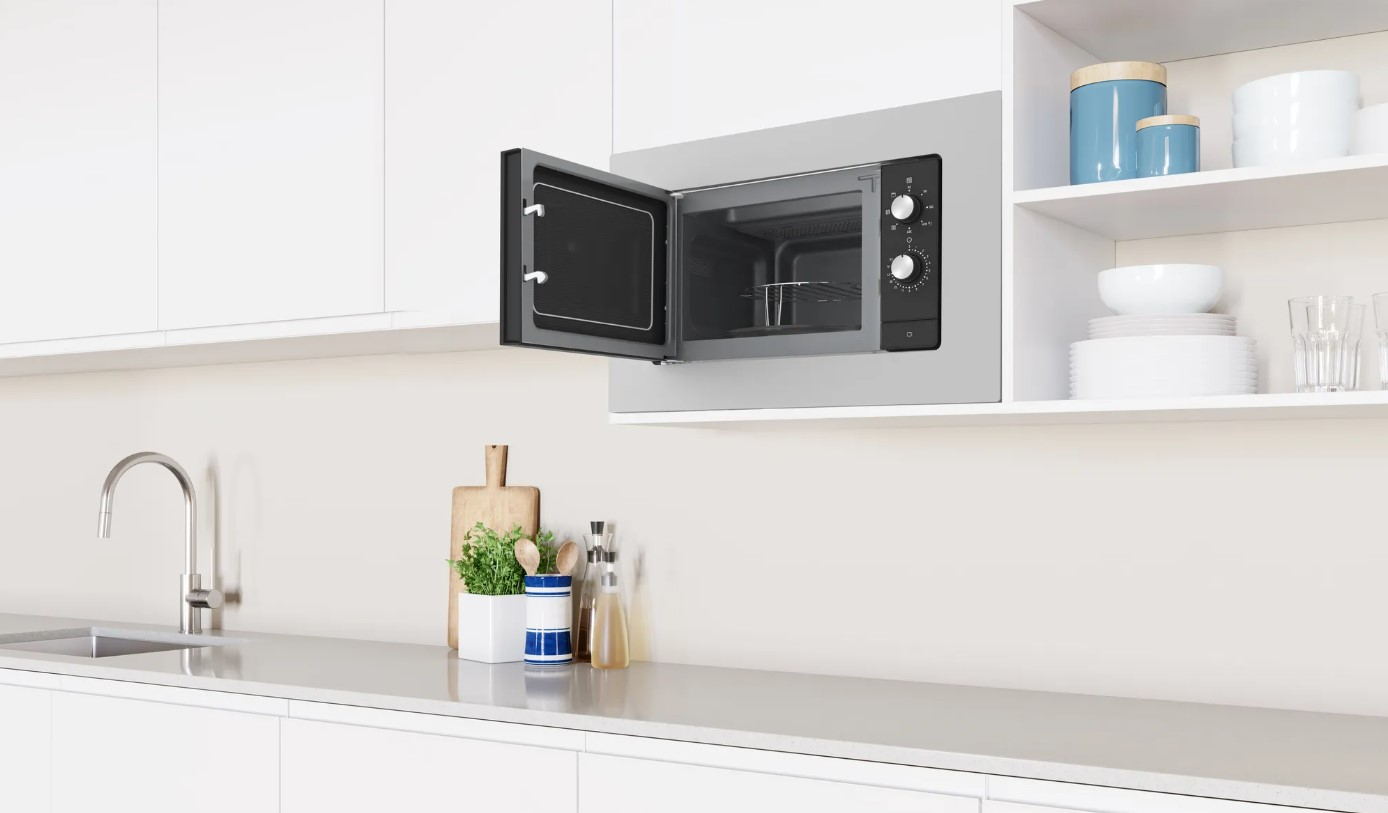 Horno microondas montado en un armario de cocina blanco. Puerta abierta.