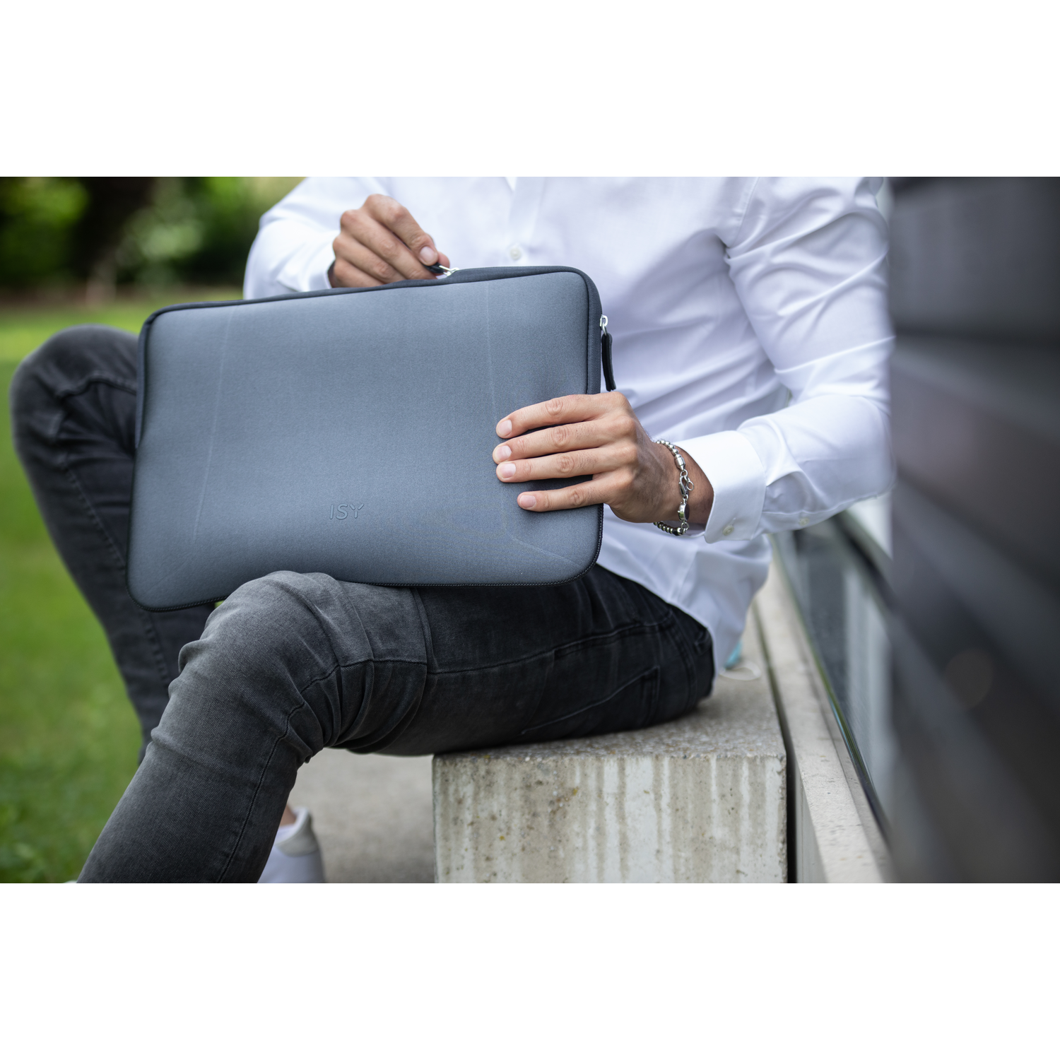 Person holding a grey laptop case, with a person in the background.