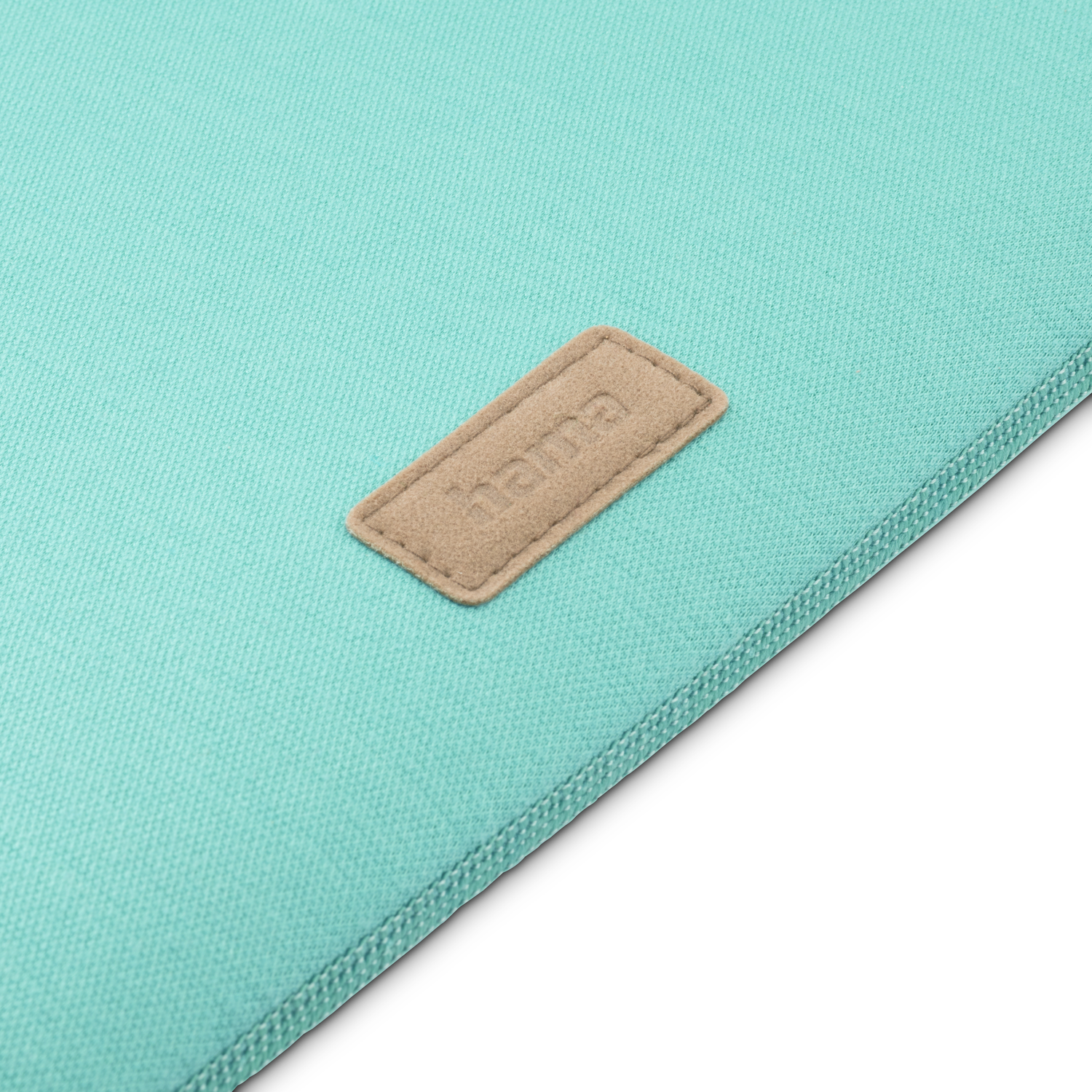 Close-up van een teal laptophoes met een bruin label met de tekst "hama".