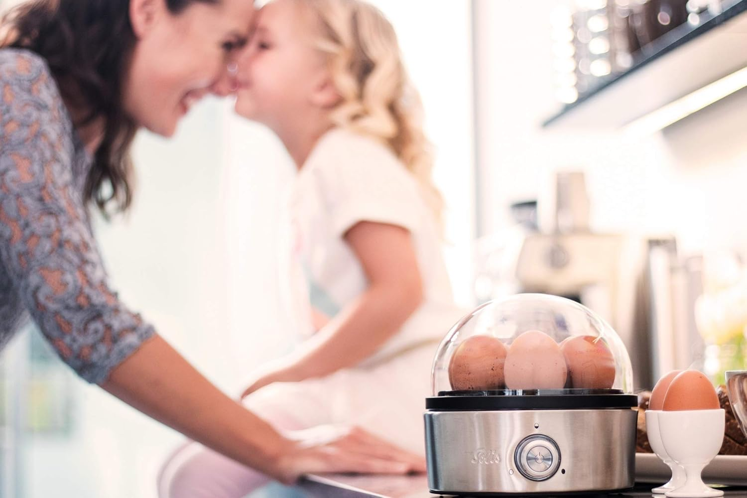 Una donna e una bambina sorridono vicino a un cuoci uova con le uova all'interno.