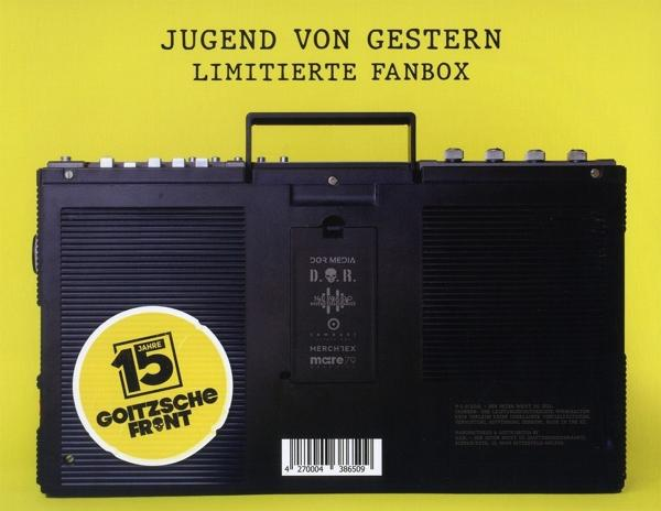 Schwarze Boombox mit großem gelben Aufkleber. Text auf Deutsch, Knöpfe und Griff sichtbar.