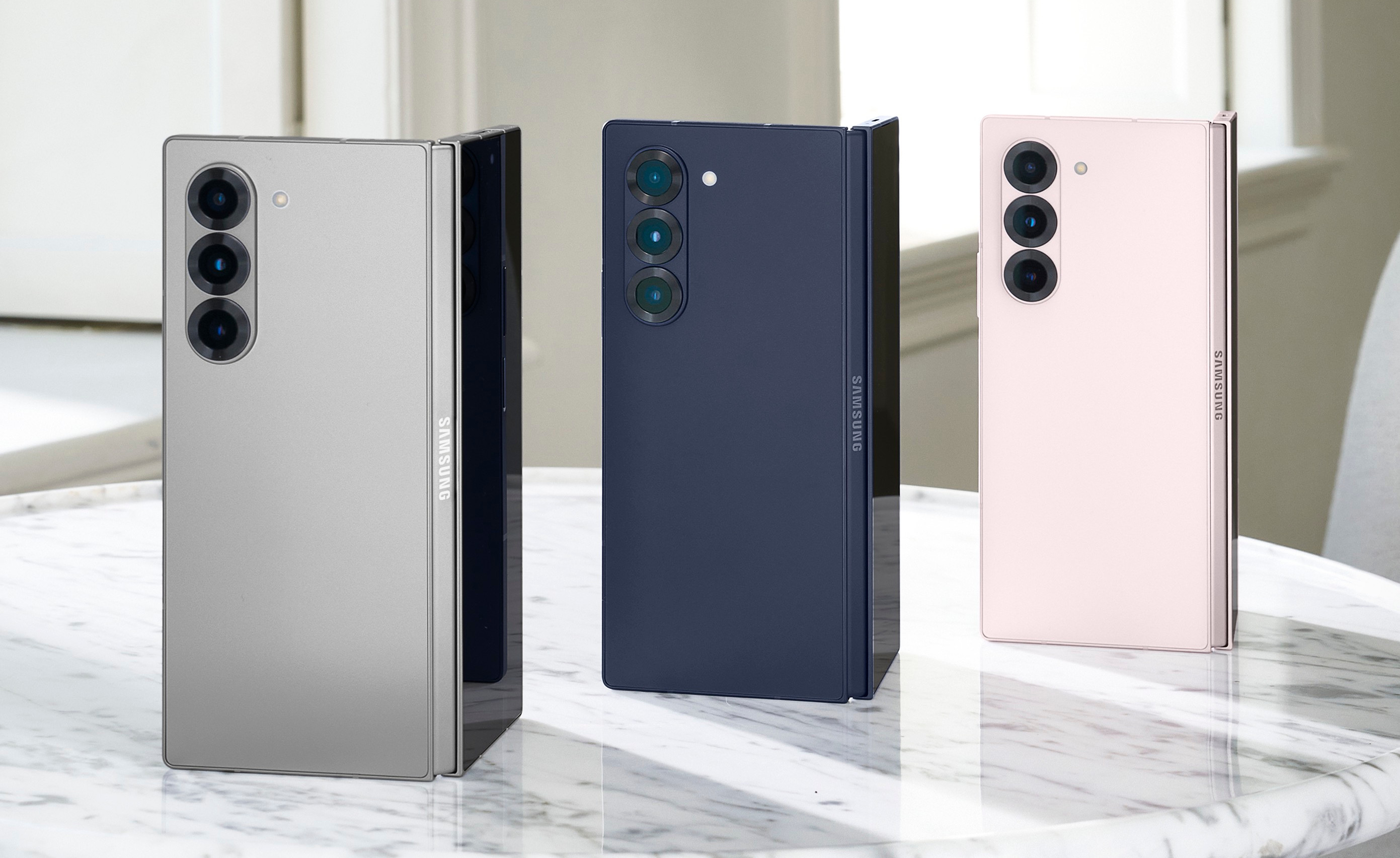 Trzy składane telefony w kolorze srebrnym, niebieskim i różowym.