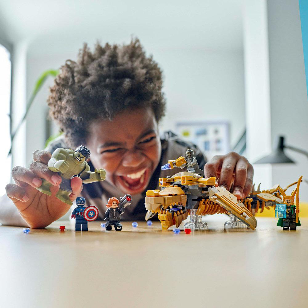 Ein Kind spielt mit einem Lego-Set mit Superhelden-Charakteren und einem Drachen.
