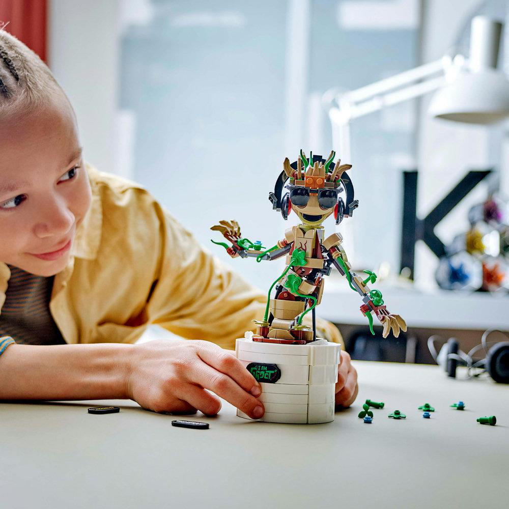 Ein Kind baut eine Lego Groot Figur, lächelnd, mit ein paar Teilen drumherum.