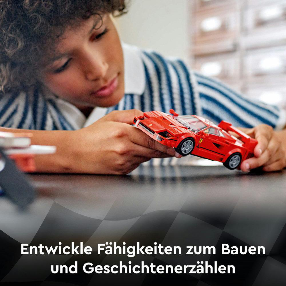 Ein Junge spielt mit einem roten Lego-Automodell auf einem Tisch.