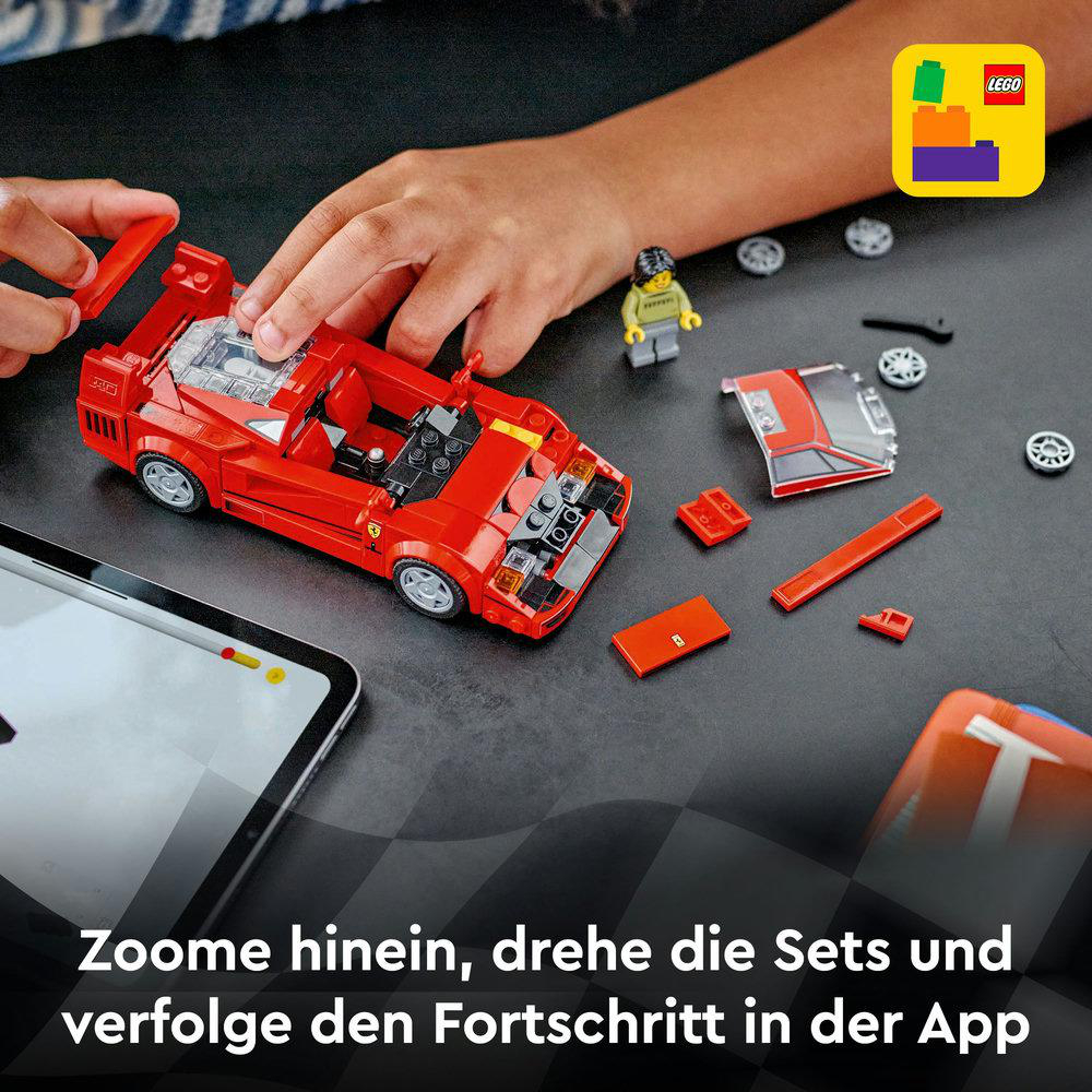 Kinderhände montieren ein rotes Lego-Auto. Ein Tablet zeigt die Bauanleitung des Autos an.