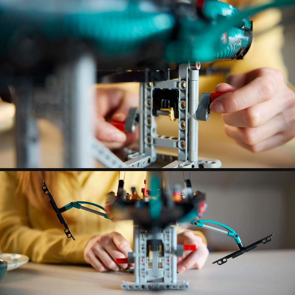 Hände, die eine Lego-Maschine zusammenbauen. Die Maschine ist grau, mit teal und roten Akzenten.