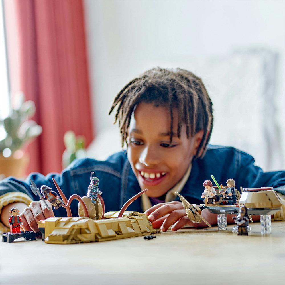 Junge spielt mit Lego Star Wars Set, mit Figuren und Fahrzeug.