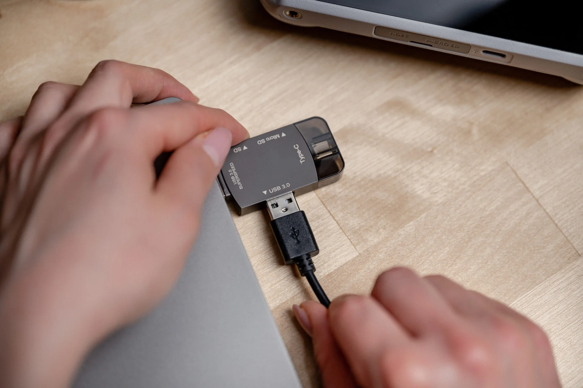 Hände, die einen Kartenleser in einen Laptop stecken, USB-Kabel angeschlossen.