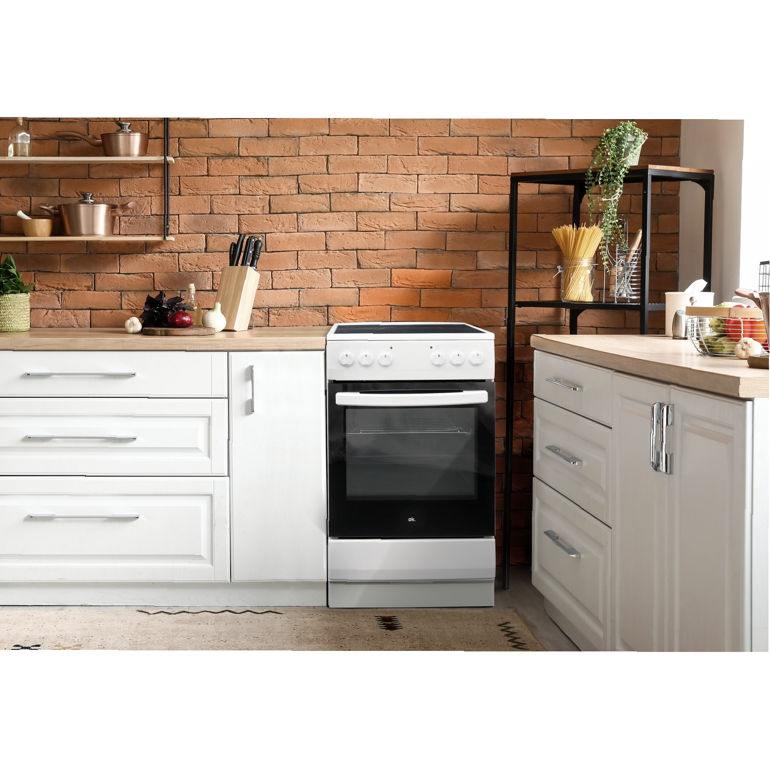 Een witte oven in een keuken met witte kasten, een bakstenen muur en een vloerkleed.