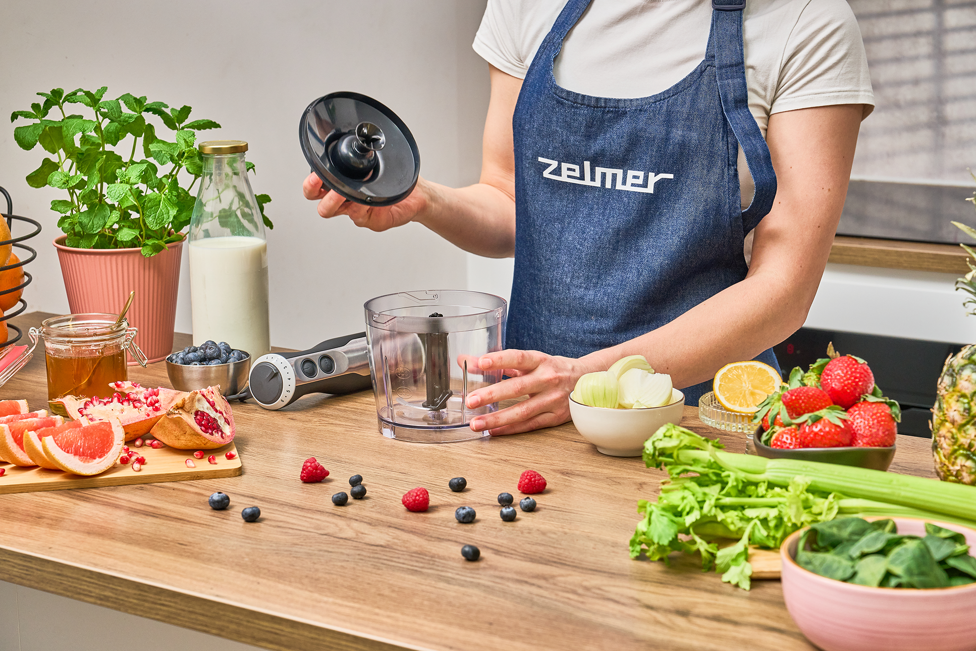Nő smoothie-t készít gyümölcsökkel és turmixgéppel.