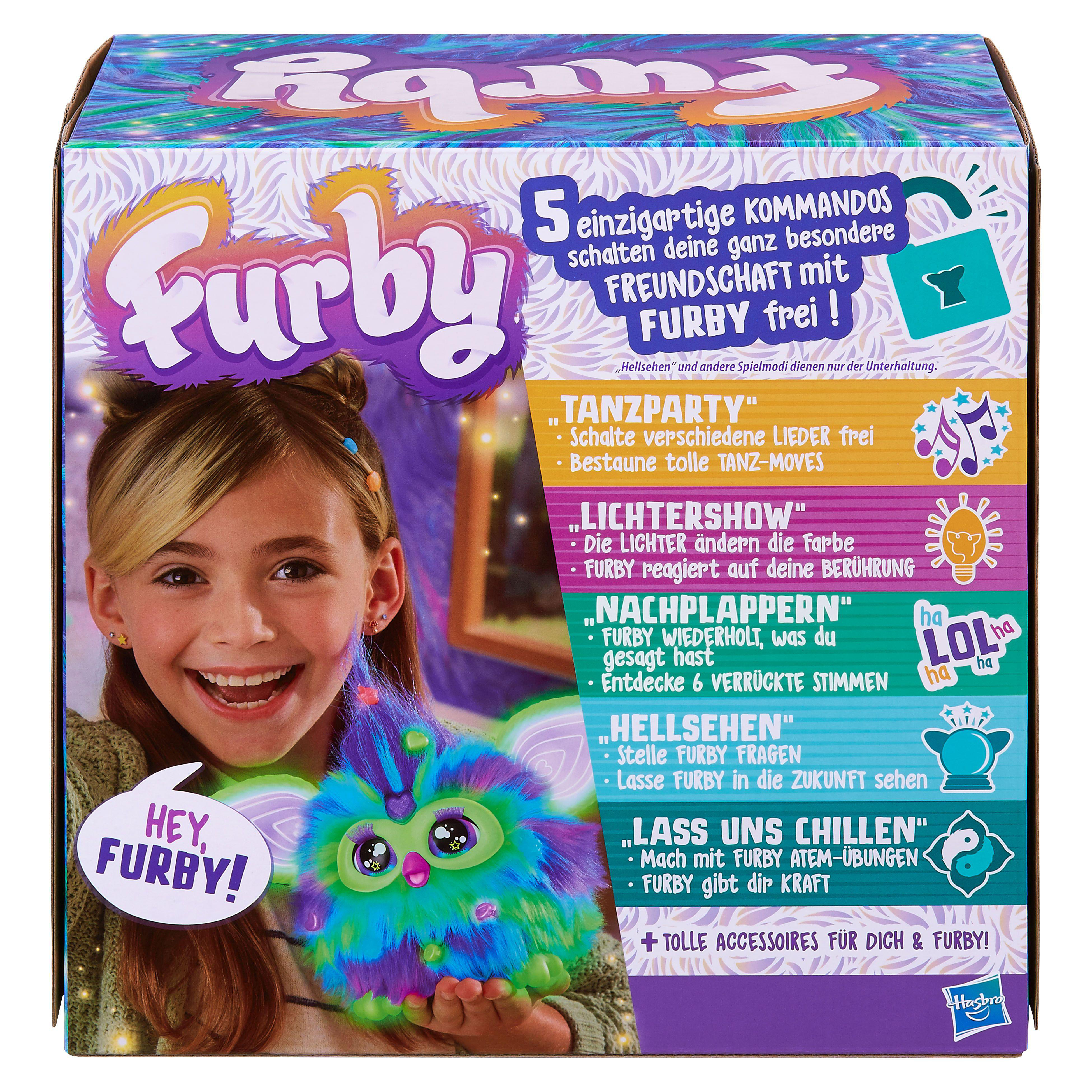 Ein Mädchen hält ein Furby-Spielzeug. Das Furby ist bunt. Die Verpackung zeigt verschiedene Funktionen.
