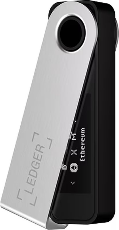 Ein Ledger Hardware-Wallet wird gezeigt, silbern und schwarz. Der Bildschirm zeigt 'Ethereum'. Die Oberseite hat einen kreisförmigen Anschluss.