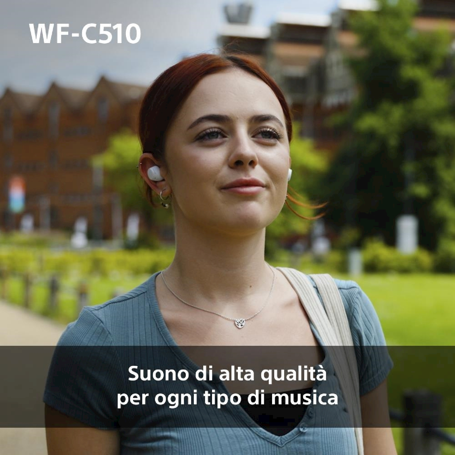 Donna con auricolari che guarda in alto davanti a un edificio.