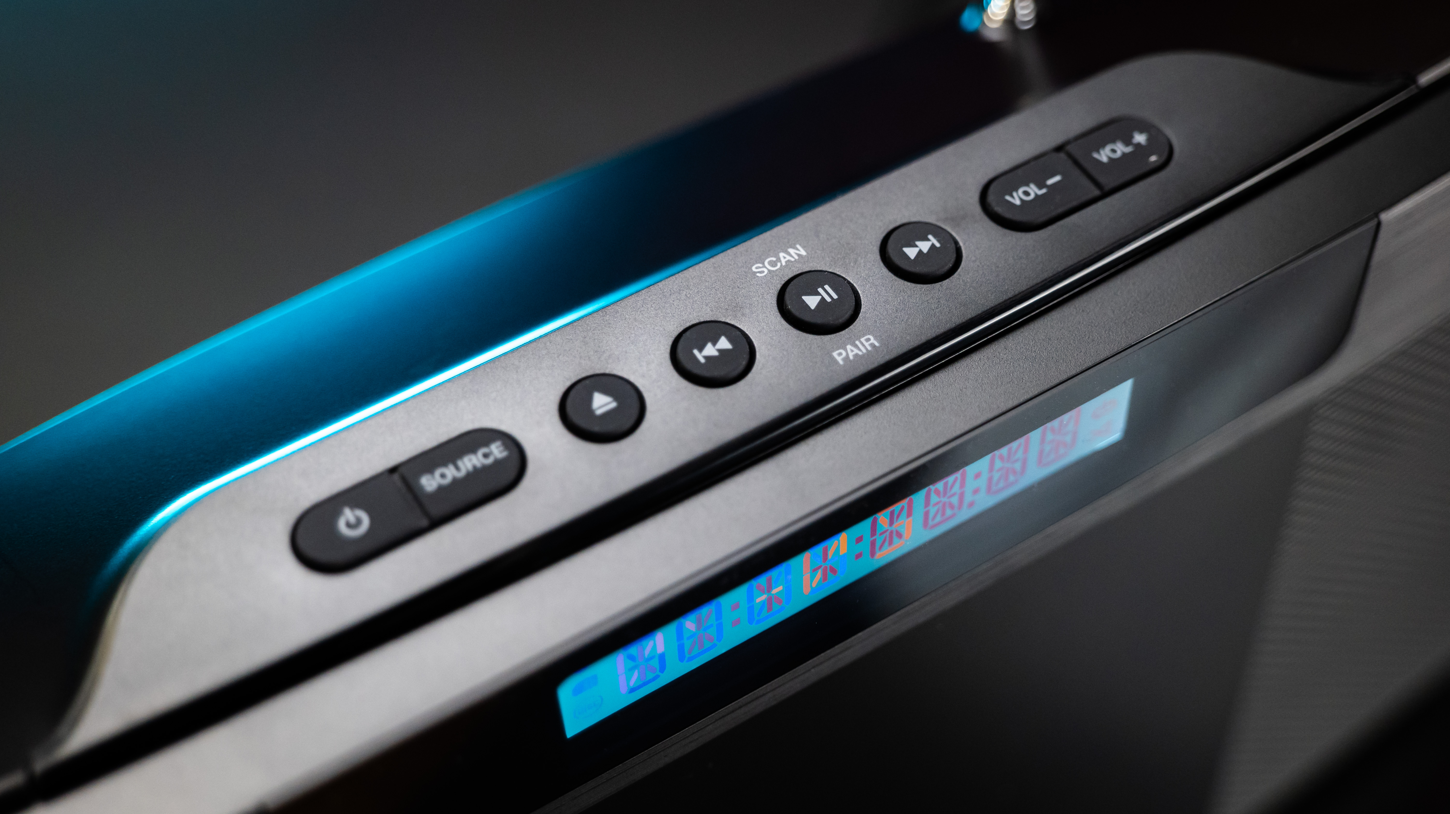 Zbliżenie czarnego panelu sterowania głośnikiem z przyciskami i wyświetlaczem symboli.