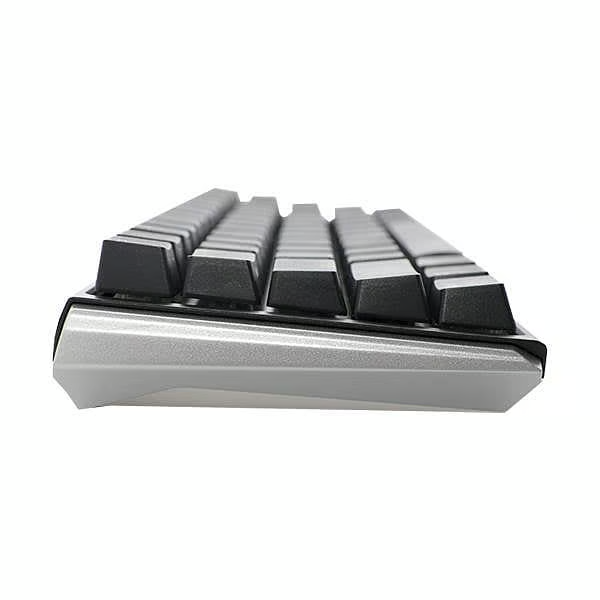 Primer plano de un teclado mecánico con teclas negras, base gris claro, sobre una superficie blanca.