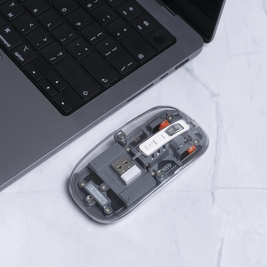 Un mouse trasparente che mostra i componenti interni, posto su un laptop.